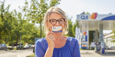 Een vrouw die een smileskaart voor haar mond houd. 