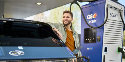 Man staat naast Alpitronic HYC400 (400 kW DC) met Q8 branding om zijn auto te laden
