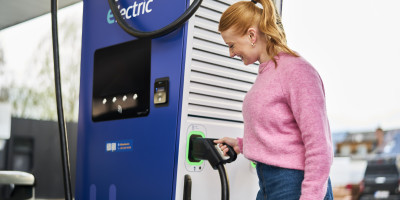 Une femme débranche le chargeur électrique Q8 pour le brancher sur sa voiture.